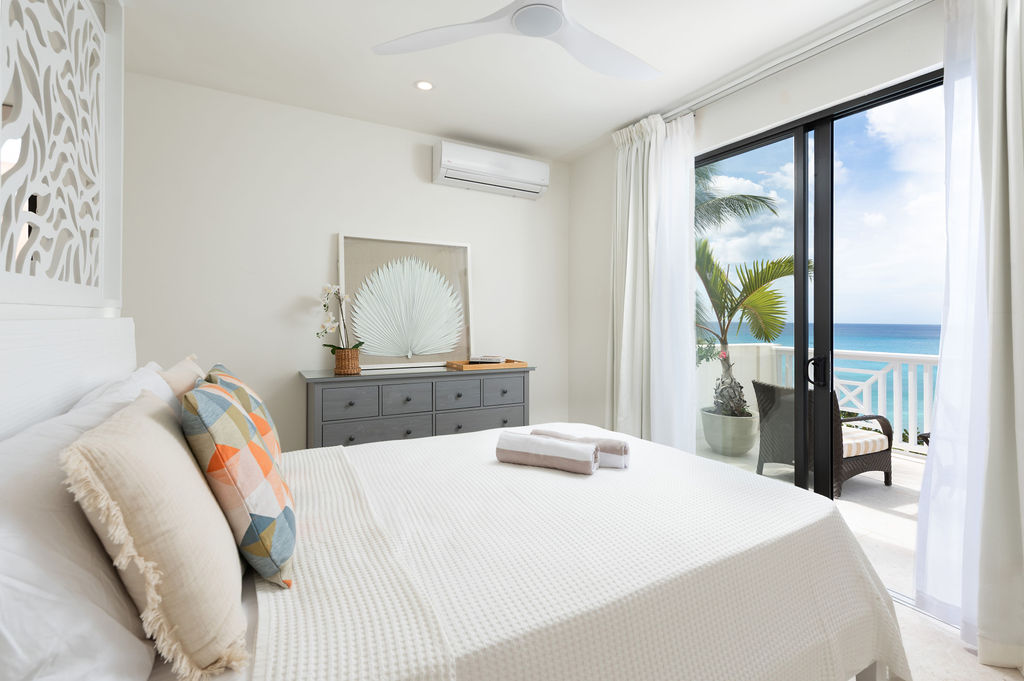 Bedroom opening to a sea-view balcony at Calico, a beachfront villa in St James, Barbados