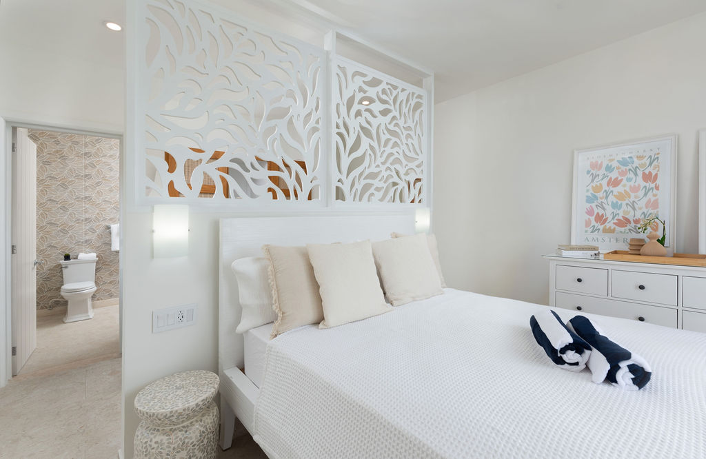 Bedroom with white headboard and en-suite at Calico, a beachfront villa in St James, Barbados