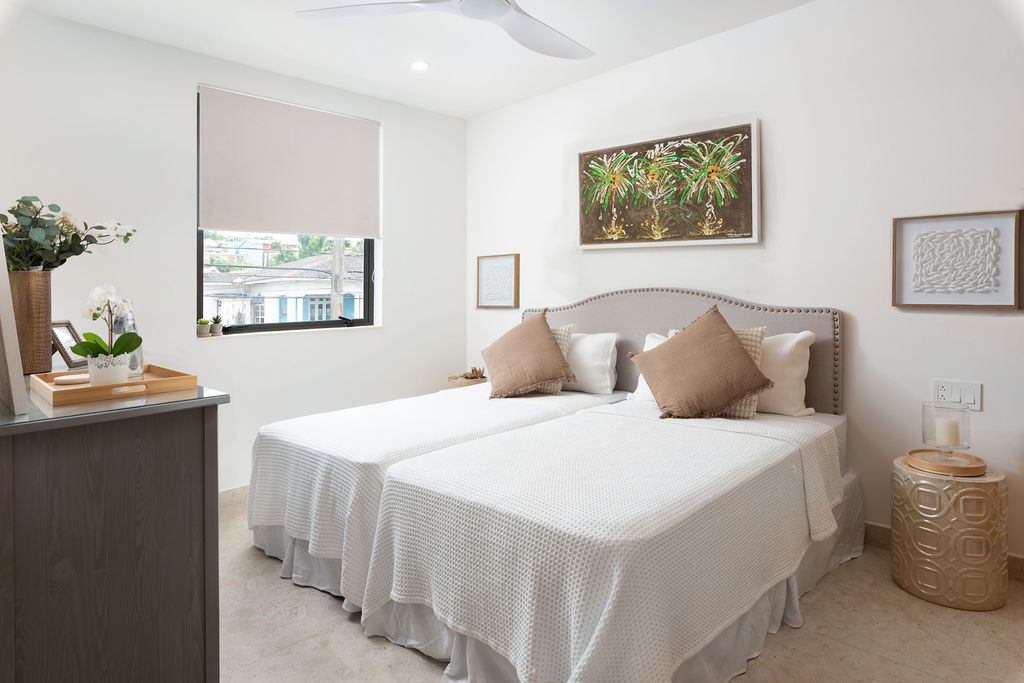 Bedroom with an upholstered bed and artwork at Calico, a beachfront villa in St James, Barbados
