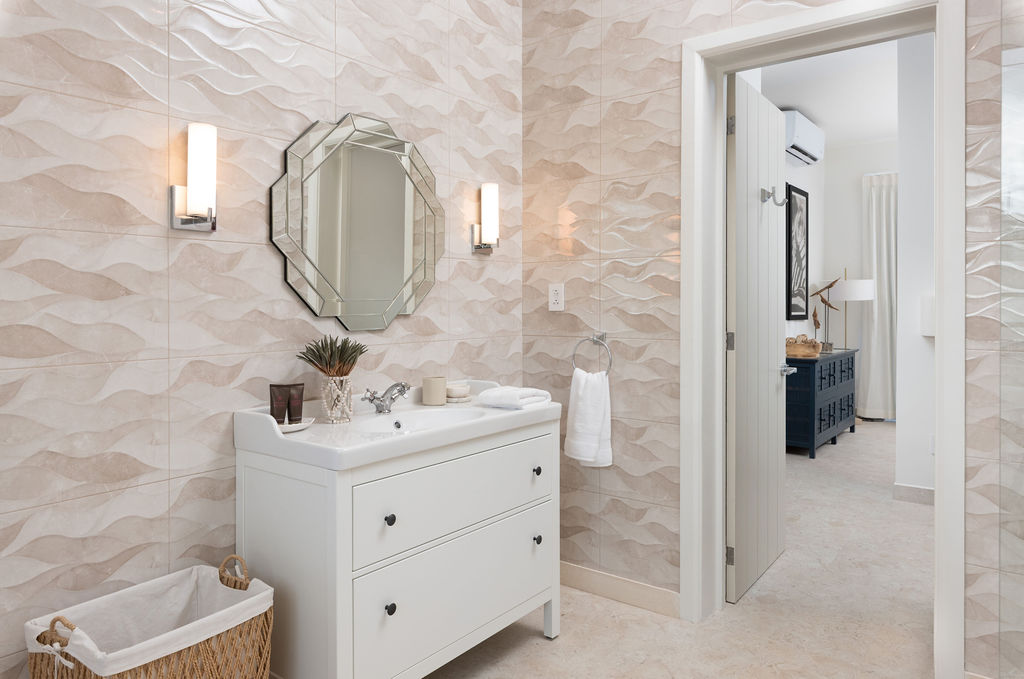 Bathroom with round mirror and vanity at Calico, a beachfront villa in St James, Barbados